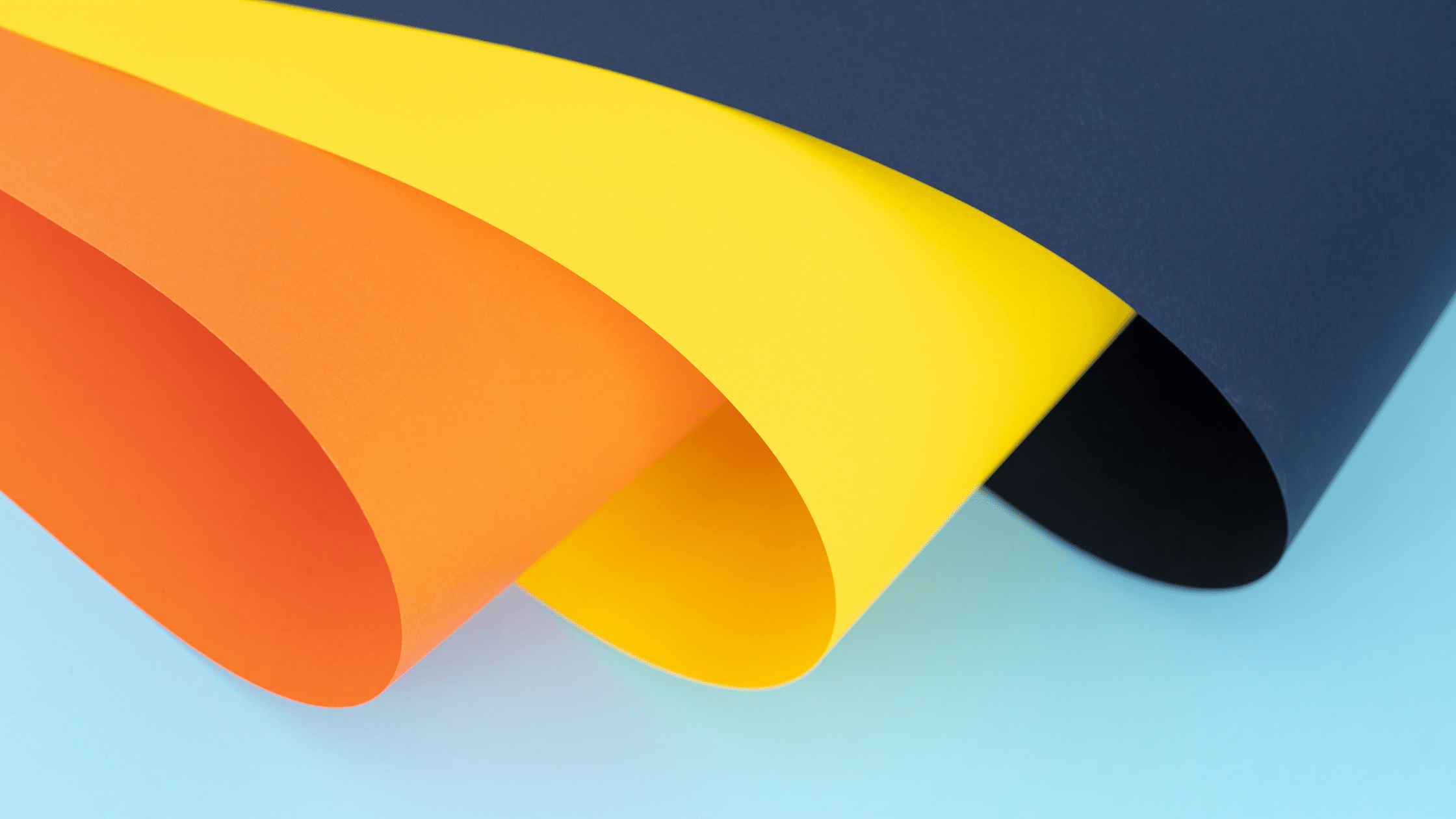 Orange, yellow, and blue construction paper folded halfway against a light blue background